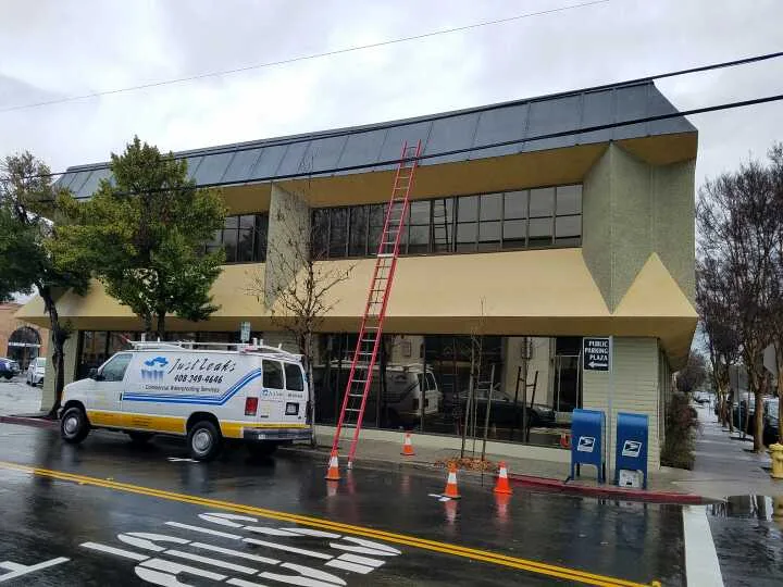 Just Leaks emergency service van responding to a commercial roof leak in the rain